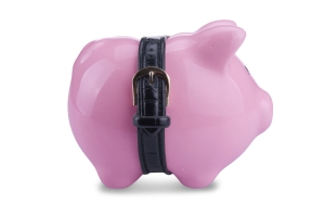 conceptual image of a piggy bank with tight belt isolated on white background