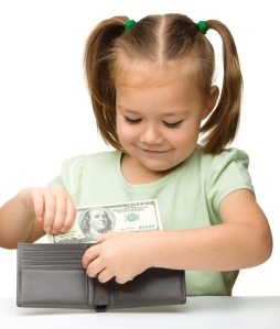 Cute little girl is putting dollars in purse, isolated over white